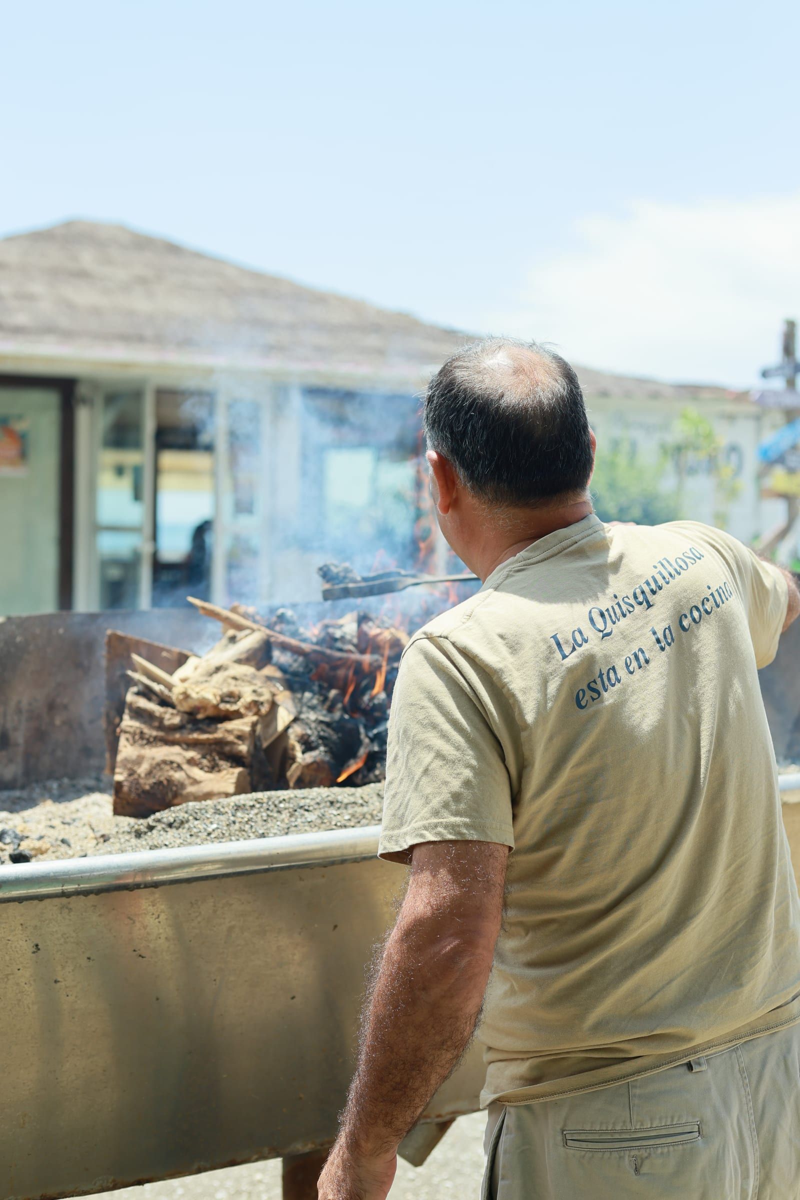 Köchin am Grill inmitten von Holzfeuer und Rauch.